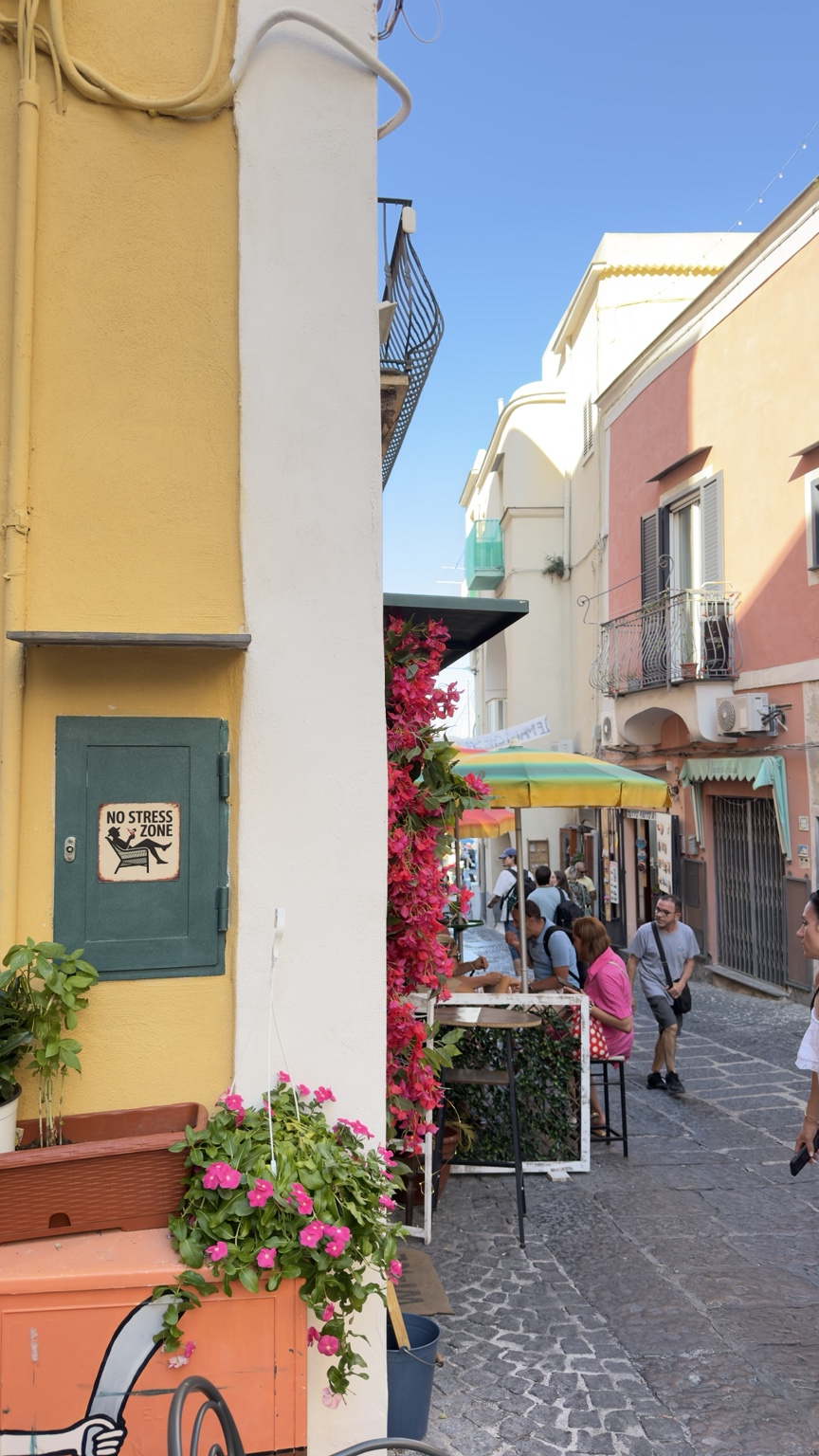 Una strada tra case colorate e tavolini all’aperto